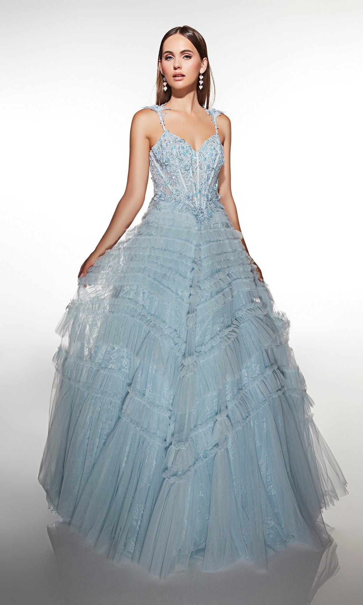 A woman poses against a white background in the Alyce 62058 long formal dress—a light blue ball gown featuring a lace bodice, ruffle accents, and elegant earrings.